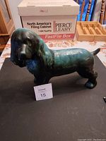 Front and side angle view of blue-green ceramic dog figurine showing detailed form and glossy glaze.