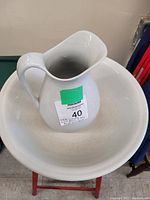 White ceramic jug placed inside a large white ceramic bowl, both items shown in good condition without cracks or chips.