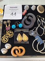 Lot of costume earrings on black background with auction lot tag visible