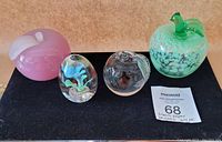 Full set of four glass paperweights: two apple-shaped and two oval-shaped, displayed on black surface.