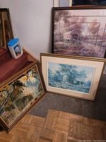 Three framed artworks shown together: oil painting by Fredrix, and two prints, one of a wooden bridge with church, and one of a house.