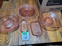 Top-down photo showing full set of six pieces of pink Depression glassware on wooden surface.