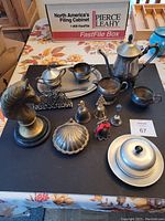 Photo of entire lot items on a table including silver plated tea set pieces, decorative items, and brass horse bust statue.