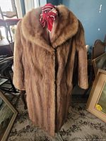 Front view of the brown mink coat on a dress form showing shawl collar and full length.