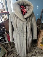 Front view of full-length white mink fur coat on display, showing shawl collar and even fur texture.