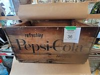 Front view of vintage wooden crate with printed Pepsi-Cola logo and text, showing wear.