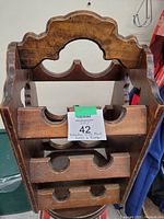 Front view showing the wooden wine rack with space for 6 bottles and a carved top edge.