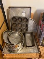 Overview of assorted bakeware items stacked including trays, pans and racks.