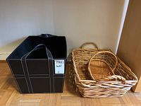 Photo showing the black faux leather storage bin alongside three natural wicker baskets of varying sizes.