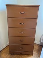 Full view of vintage painted wood dresser with five drawers standing on parquet flooring.