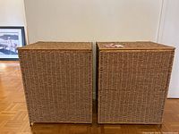 Pair of tall rectangular woven wicker hampers with lids closed, side by side.