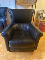 Front view of the black leather armchair showing seat cushion and backrest.