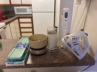 Overview of assorted kitchen items on counter including two handheld electric mixers, coffee grinder, scale, and mandolin slicer.