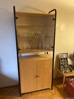 Full front view of wall unit shelving with glass shelves and cabinet below, containing glassware.