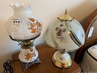 Photo showing two bed table lamps placed side by side on wooden furniture, highlighting their floral design and general size.