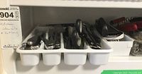 Tray with assorted cutlery including spoons, forks, and knives, mostly metal with plastic or rubber handles