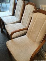 Four chairs in a row including one armchair at front, showing upholstery and wood finish