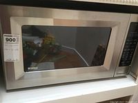 Front view of the Kenmore stainless steel microwave with door closed showing the size and sticker with measurements.