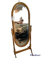 Full view of the oval floor mirror with wooden frame showing turned supports, tilt knobs and overall structure.