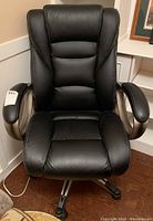 Front view of black office chair showing padded backrest and armrests.
