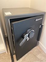 Front angled view with door partially open showing keypad, handle, SentrySafe logo, and interior shelf.