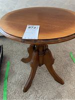 Full view of wooden round side table with pedestal base and three legs, showing overall structure and condition.