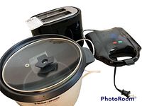 Photo showing Hamilton Beach black 2-slice toaster, Smart Home waffle maker, and Black & Decker rice cooker with glass lid and black knob.