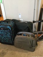 Photo showing large patterned wheeled suitcase, green duffel bag, small shoulder bag, and adjustable hand cart.