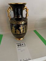 Front angled photo showing entire vase with gold handles and detailed gold figure drawings on black background