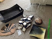 Photo showing all items in the lot: two clear hurricane glass shades, black painted wicker basket, butterfly mirror wall art with three butterflies, ceramic dish, and leaf wall plaque.