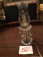 Antique glass crystal and chrome electric lamp with clear etched glass chimney, cut crystal base, and chrome elements, photographed on a table with lot number 56 in front.