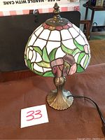 Full view of the Tiffany style lamp showing the stained glass shade and metal base.