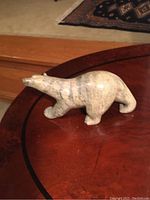 Left side view of carved stone polar bear sculpture on wooden surface