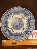 Front view of the blue and white Spode collector plate showing detailed continental landscape and ornate border design, ruler for scale showing plate measures approx. 11 inches.