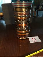 Full vase on wood table with size tape showing height.