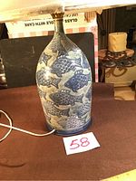 Full view of ceramic lamp base with blue fish pattern, showing lamp cord and handwritten lot number card 58.
