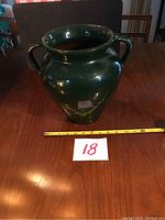 Front view of the green vase showing its overall shape and size with measuring tape indicating approximately 9 inches across the handles.