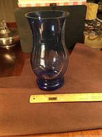Side view of the large blue glass vase with a measuring ruler at its base showing the height close to 12 inches
