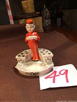 Front view of the vintage bellhop porcelain figurine holder with ashtray and multiple holes on base for holding items.