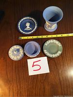 Overview photo of the Wedgwood Jasperware set showing a goblet, two plates, and a lidded bowl on a wooden table with measuring tape.