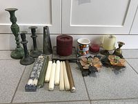 Full view of all candle holders and candles arranged on the floor showing variety of materials and styles.