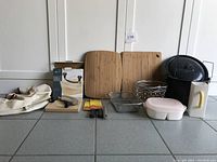 Full overview of the kitchenware lot items including cutting boards, kitchen knives, storage containers, a baking dish, napkin holders, and a stock pot.