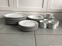 Top view showing plates, bowls, cups and saucers arranged in stacks, highlighting quantity and condition