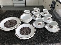 Full set of Corelle dinnerware arranged on countertop including plates, bowls, cups, and saucers