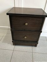Front view of the cedar-toned end table showing two drawers with small round brass knobs and a clean, simple design.