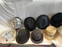 Eight assorted men's hats displayed together, showing variety in style and pattern.