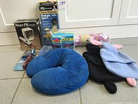 Lot contents showing Waterpik box, DLX posture support brace, neck pillow, heating pad covers and electric toothbrush on tile floor.
