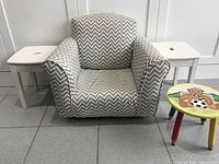 Front view of kids fabric rocking chair with grey and white chevron pattern and two wooden stools, one plain white and one with cartoon bear image on seat