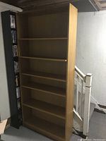 Tall rectangular oak veneer bookcase with five shelves and light wood finish.