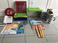 Photo showing AT&T phone, thermal coffee cups, rulers, packs of new writing paper, and plastic shelving units in various colors.